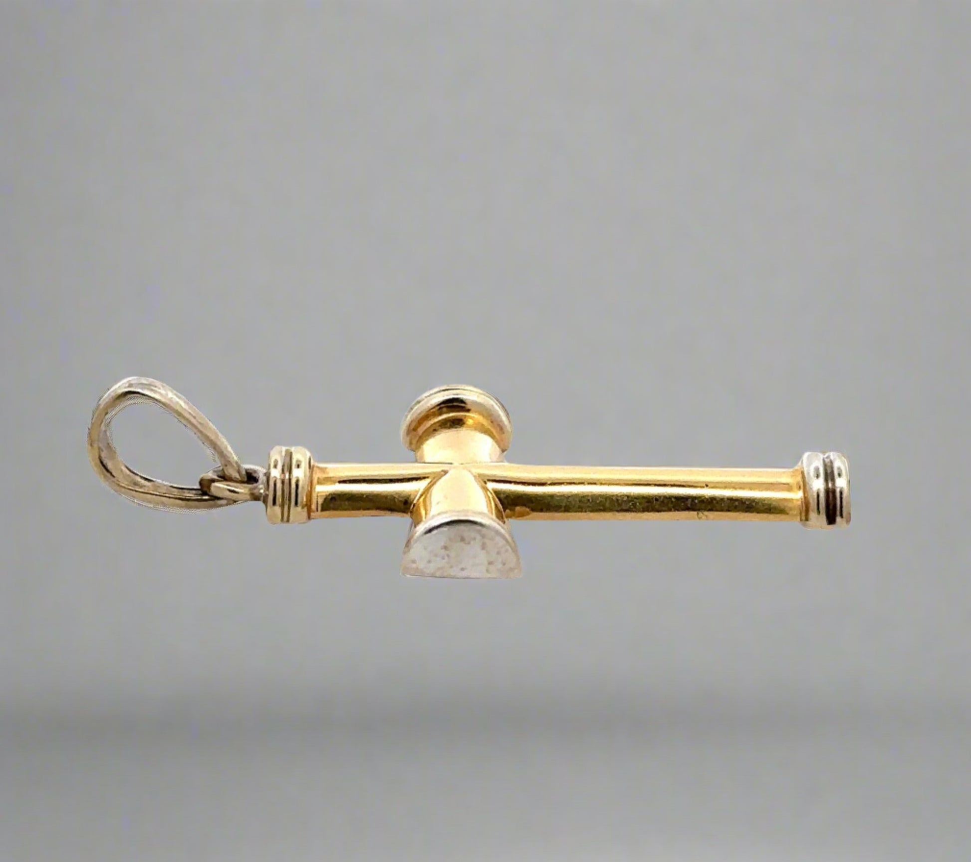 Side of yellow and white gold cross with scratches and marks on gold. Round bail