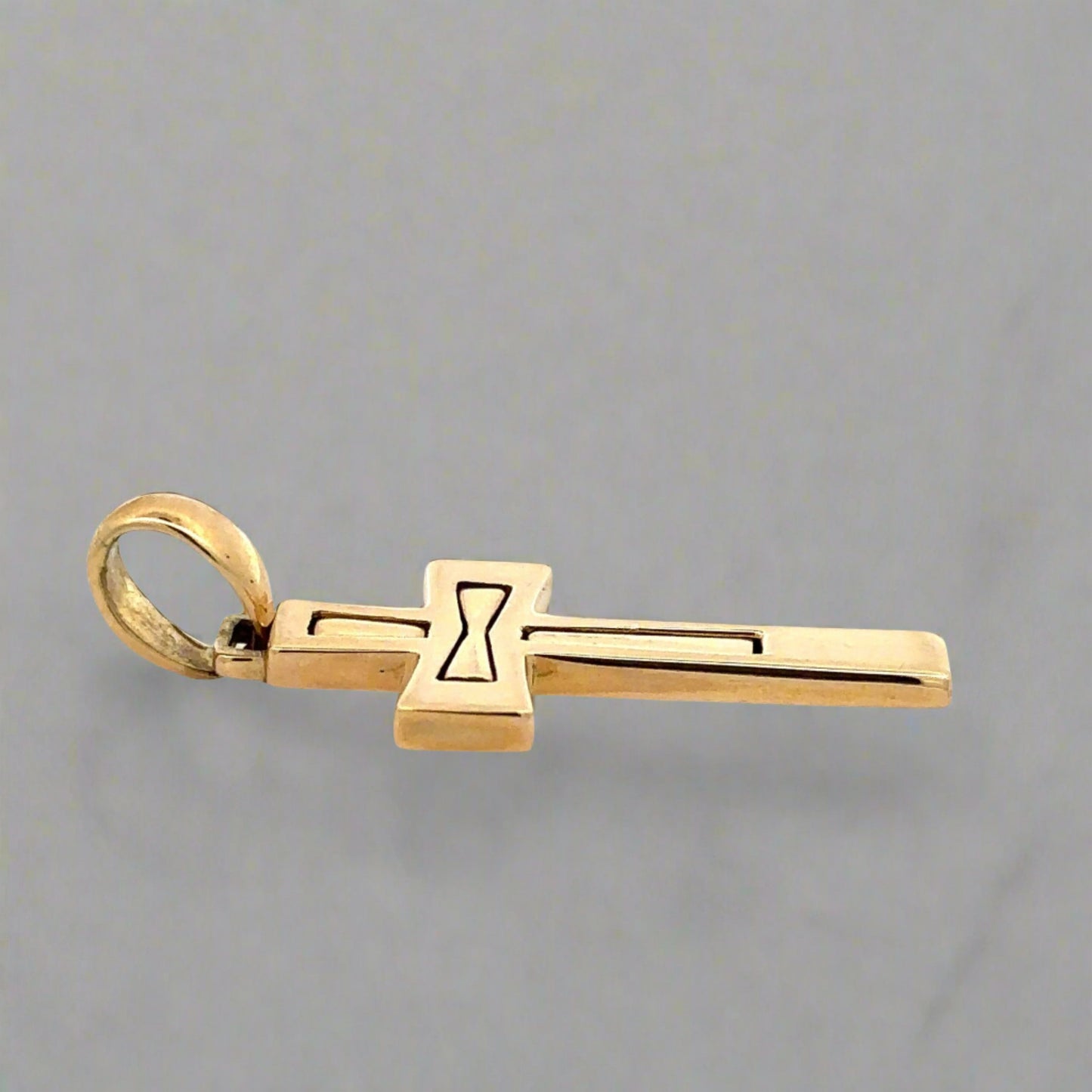 Side of yellow gold cross with round bail