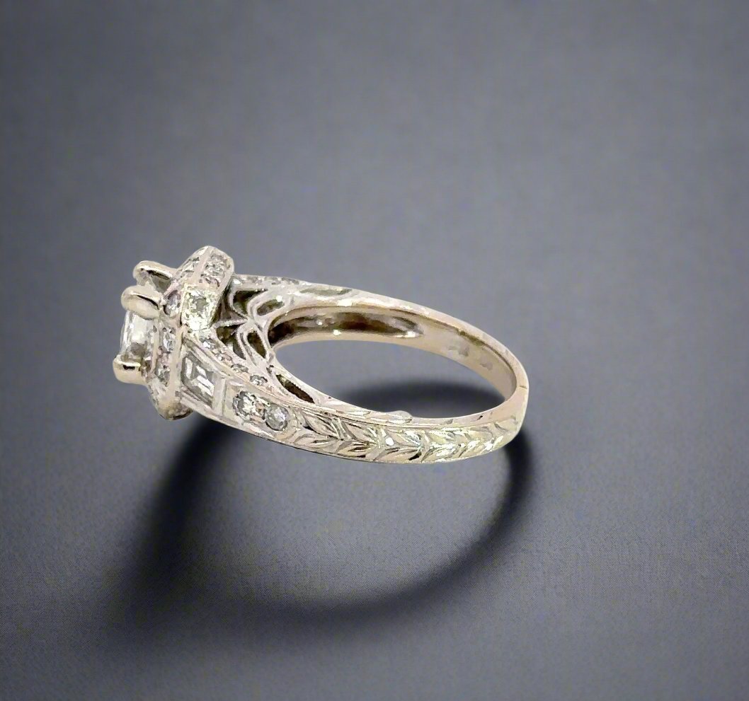 Side of ring with leaf-like engraving details on band. 1 Baguette diamond + 2 small round diamonds on side