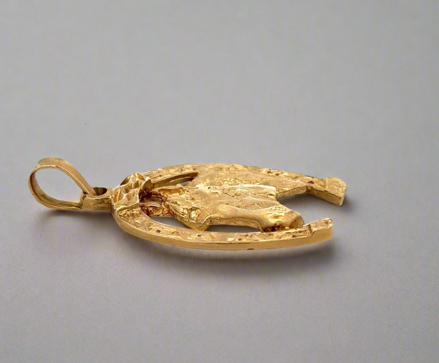 Side view of yellow gold horse shoe pendant with round bail