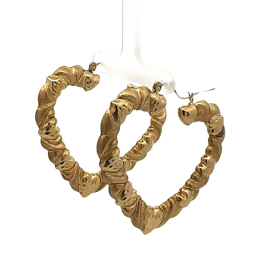 Diagonal view of yellow gold heart-shaped hoop earrings with heart detailing