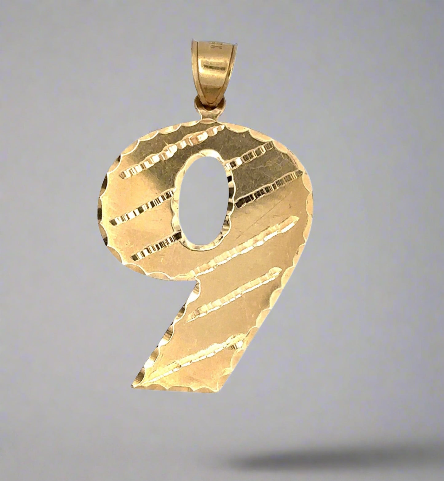 Front of yellow gold 9 pendant showing scratches on gold from handling