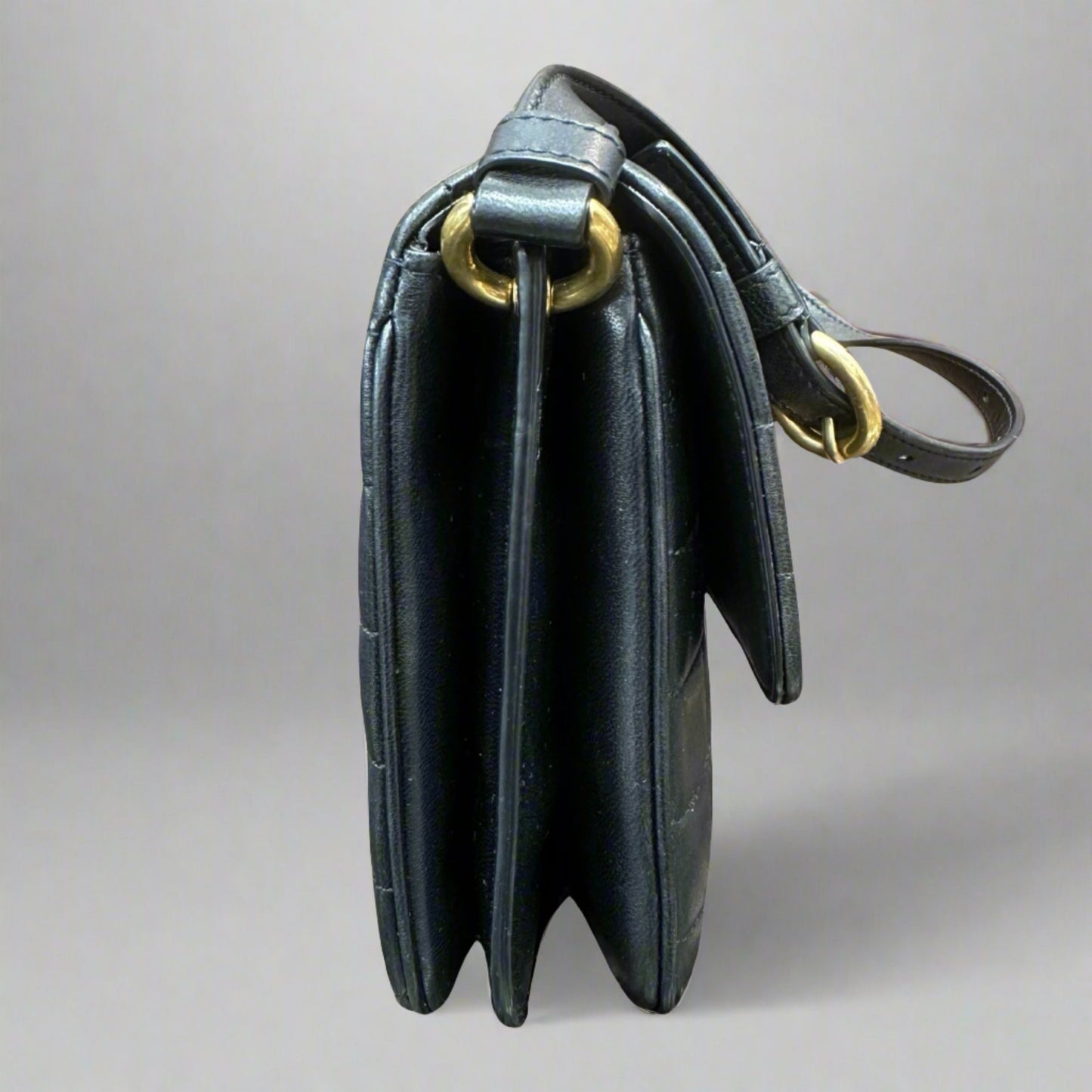 Side of black quilted bag and gold hardware