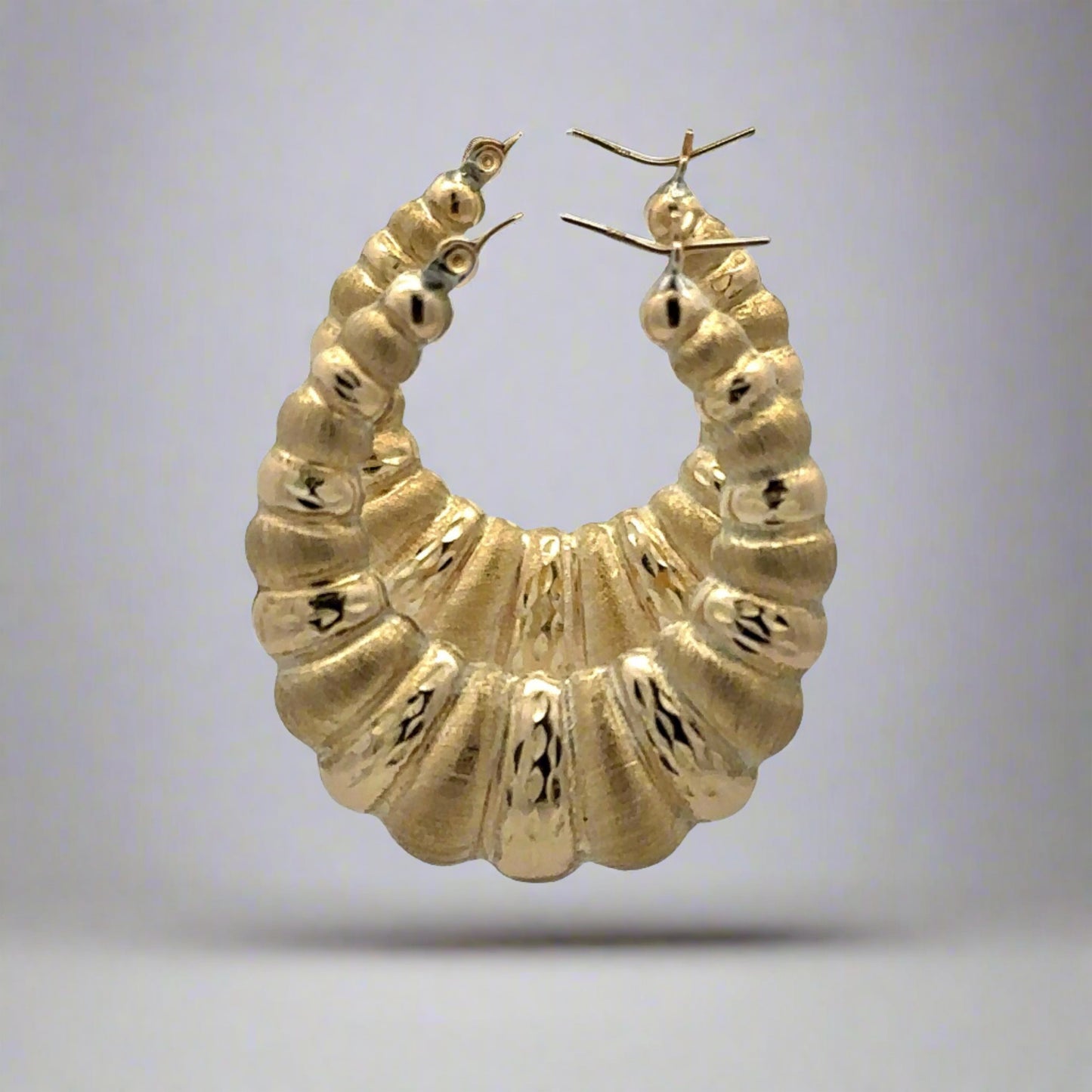 side of scalloped and brushed yellow gold hoops