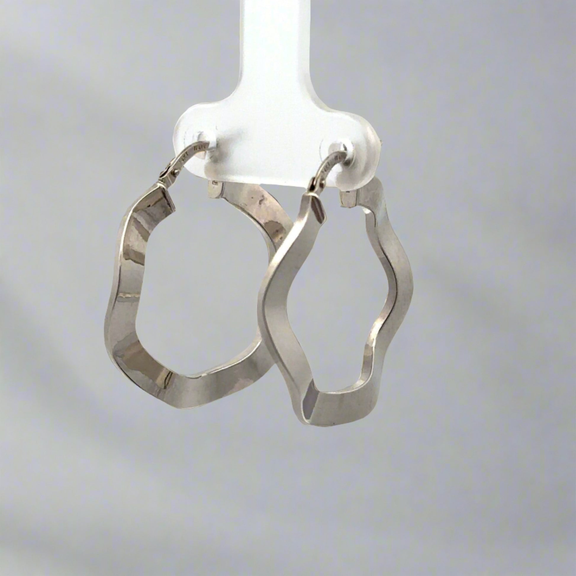 diagonal view of white gold wavy hoops