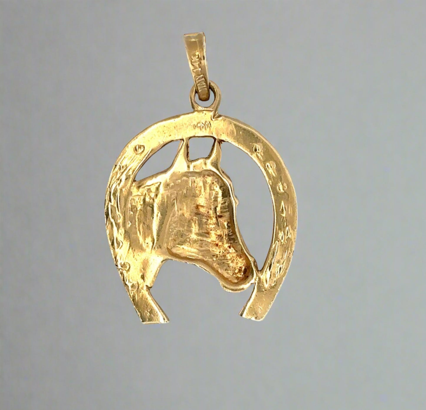 Back of horse shoe pendant with 14K stamp on bail + signs of wear on the gold.