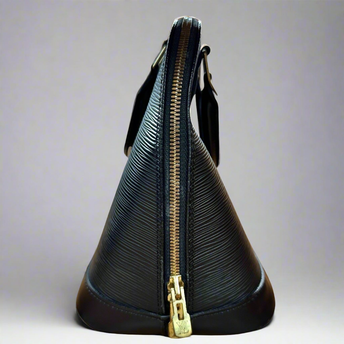 Side of black bag with gold zippers. The bag is out of shape on top