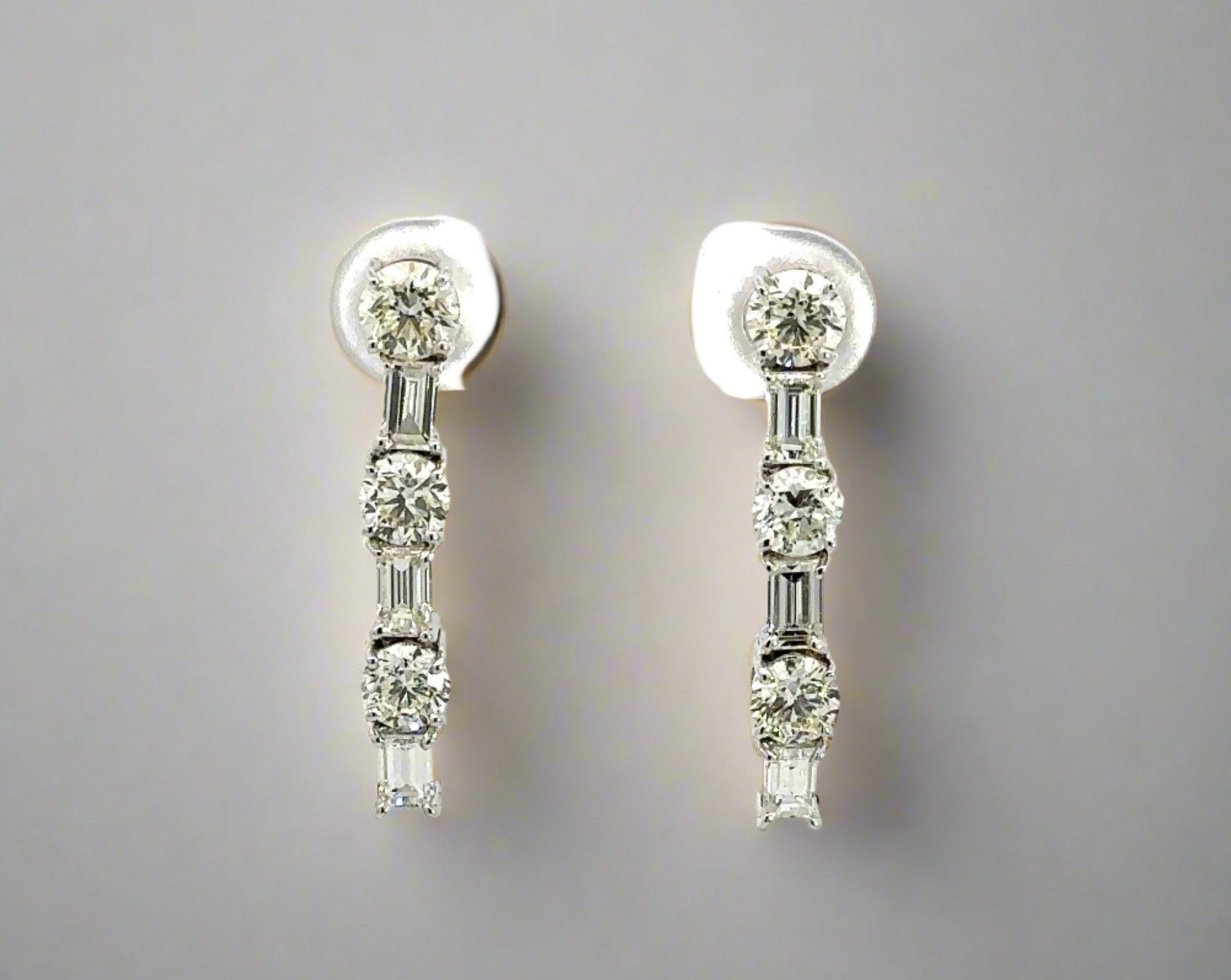 Video of white gold diamond drop earrings with 3 round diamonds alternating with 3 emerald cut diamonds