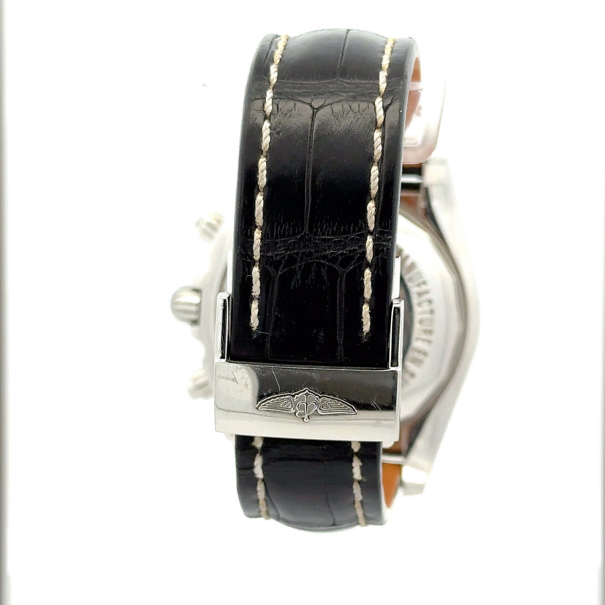 Back of the watch showing the leather band and the stainless steel clasp that holds the band. Black leather band shows wear. Clasp shows scratches.