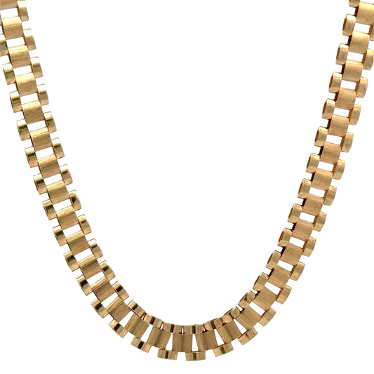 A gold-toned rolex link chain necklace with a wide, textured rectangular link design, shown against a plain white background.