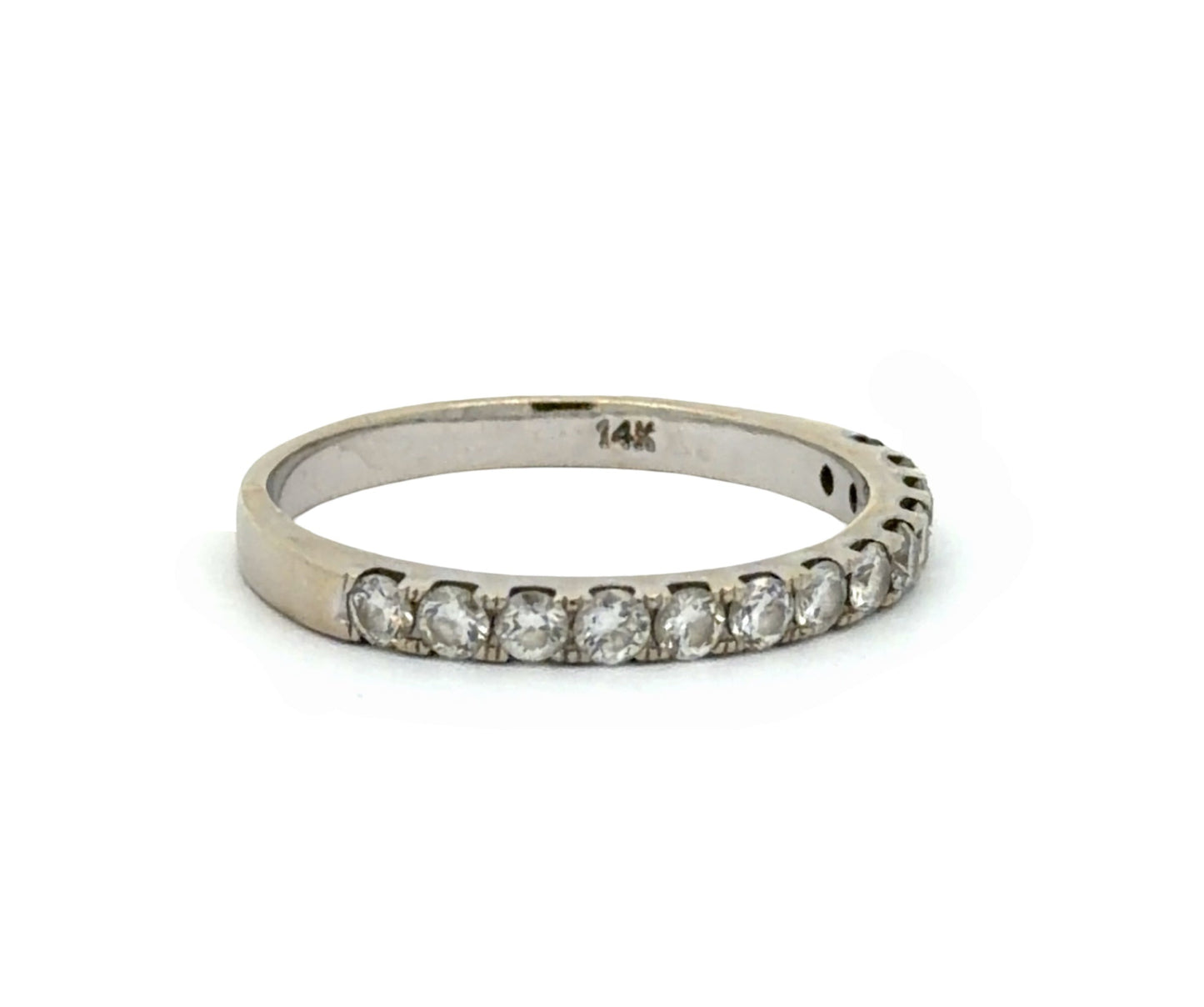 A white gold ring with a row of round-cut diamond on one half, shown against a plain white background. The inside of the band is stamped with '14K'.and 