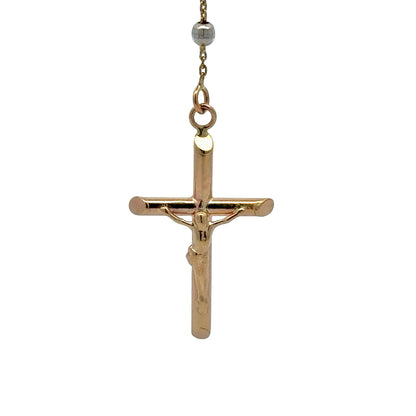 A yellow gold crucifix pendant necklace with a detailed figure of Jesus on the cross, suspended from a  gold chain shown against a plain white background.