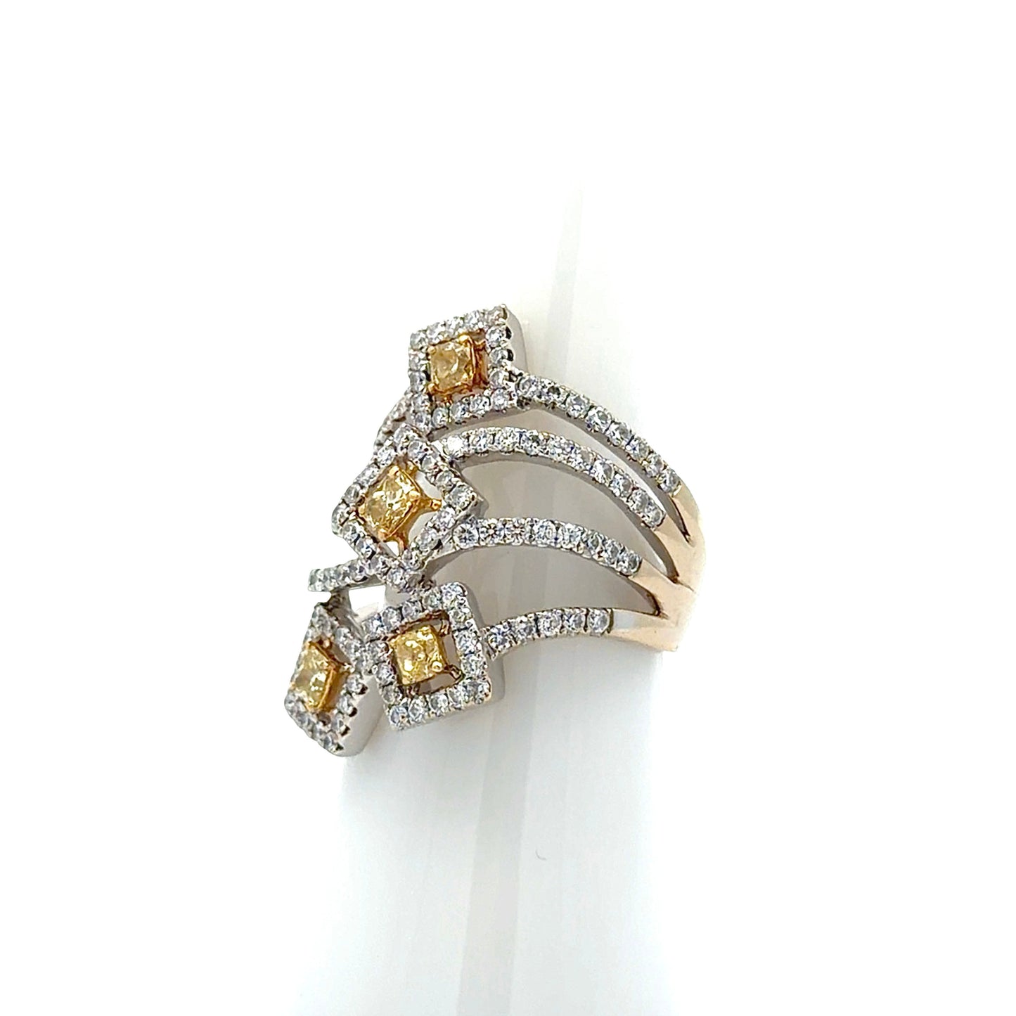 A multi-band ring with yellow and white diamonds, displayed on a white cone stand against a white background.