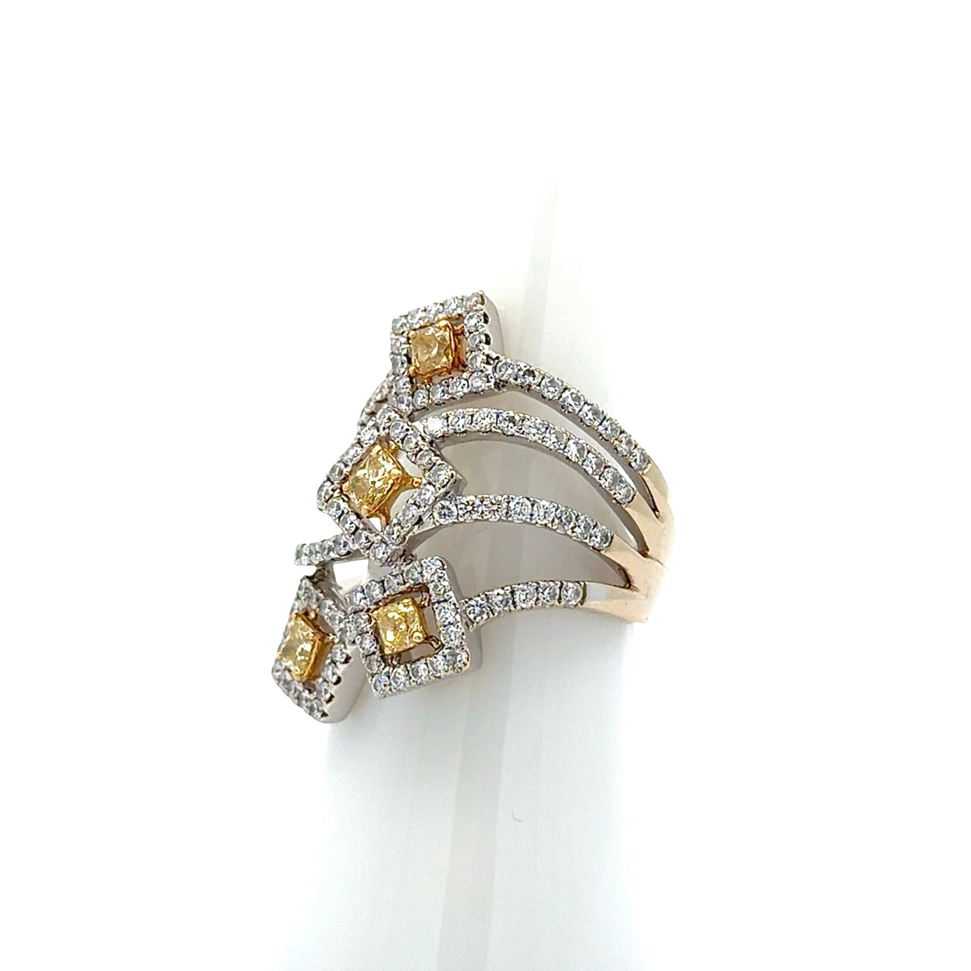 A multi-band ring with yellow and white diamonds, displayed on a white cone stand against a white background.