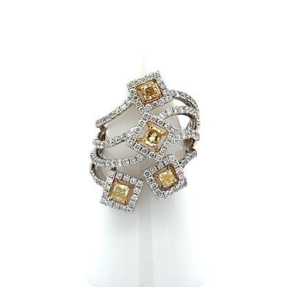 A multi-band ring featuring four square yellow diamonds surrounded by small clear stones, set in a silver-toned metal, displayed on a white cone stand against a white background.