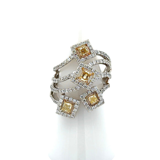 A multi-band ring featuring four square yellow diamonds surrounded by small clear stones, set in a silver-toned metal, displayed on a white cone stand against a white background.