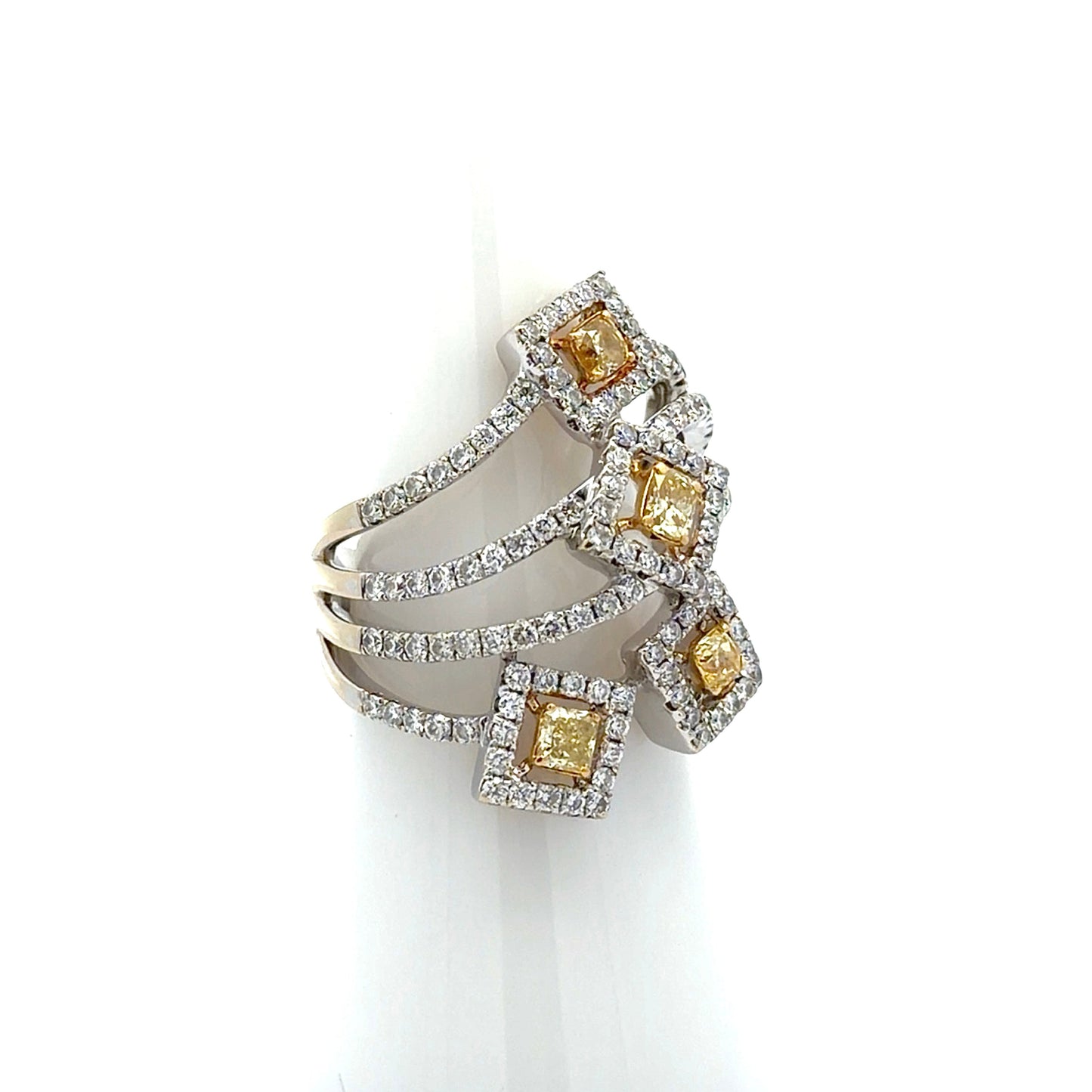 A multi-band ring with yellow diamonds and silver-colored metal settings, displayed on a white cone-shaped ring stand against a white background.
