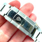 Close-up of a silver watch band with a visible brand logo on a hand.