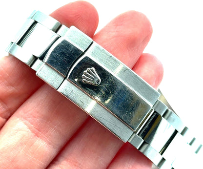 Close-up of a silver watch band with a visible brand logo on a hand.