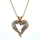 Heart-shaped diamond pendant on a gold chain against a white background