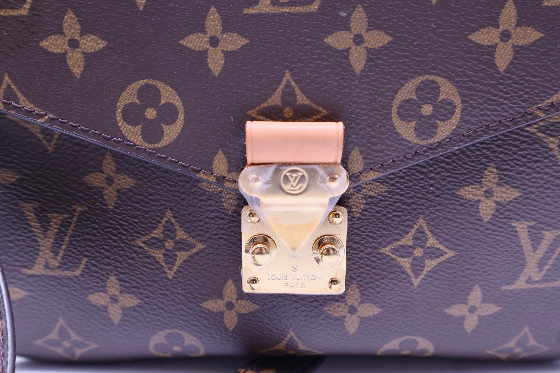 Close up of Louis Vuitton gold S-locks with plastic still on it