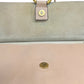 Close-up of a handbag showing the interior flap in beige suede with a gold snap button.