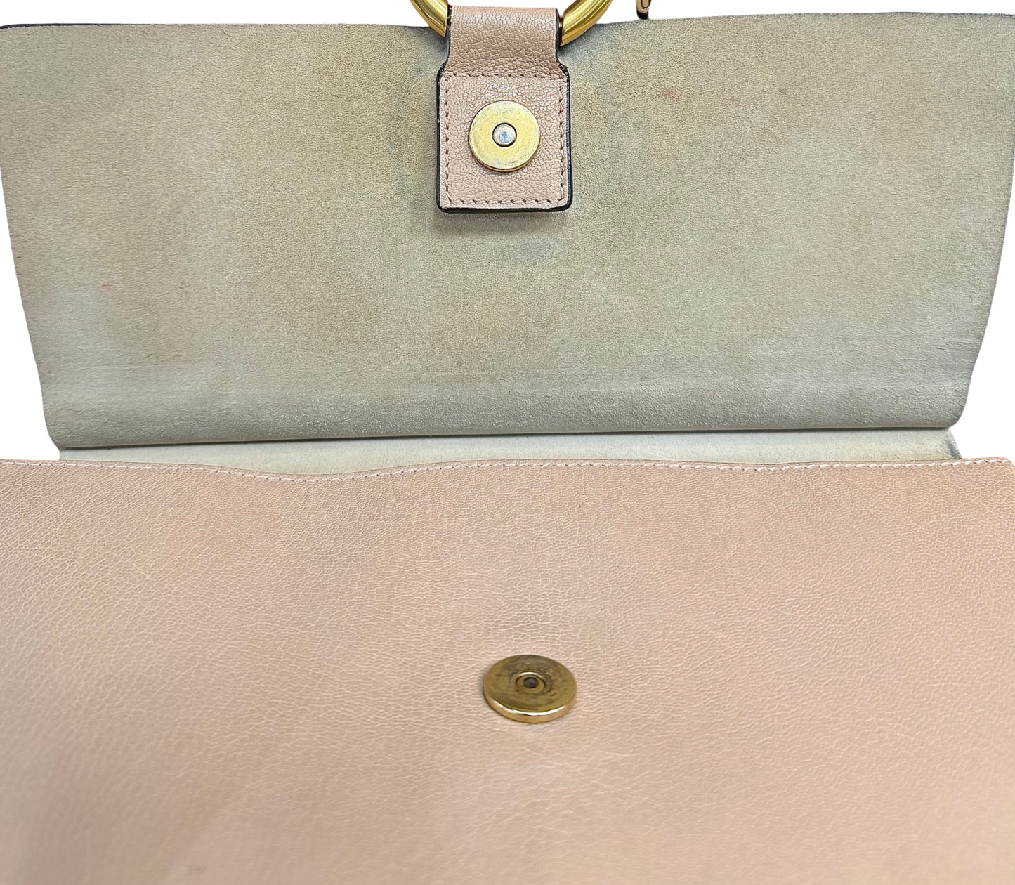 Close-up of a handbag showing the interior flap in beige suede with a gold snap button.