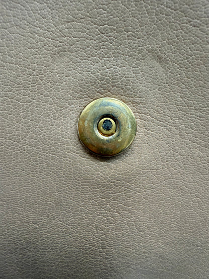 Close up of gold hardware button with scratches and discoloration