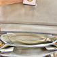 Close-up of the interior of a beige suede handbag, showing a gold zipper pocket, interior compartments, and a hand holding the top tab.