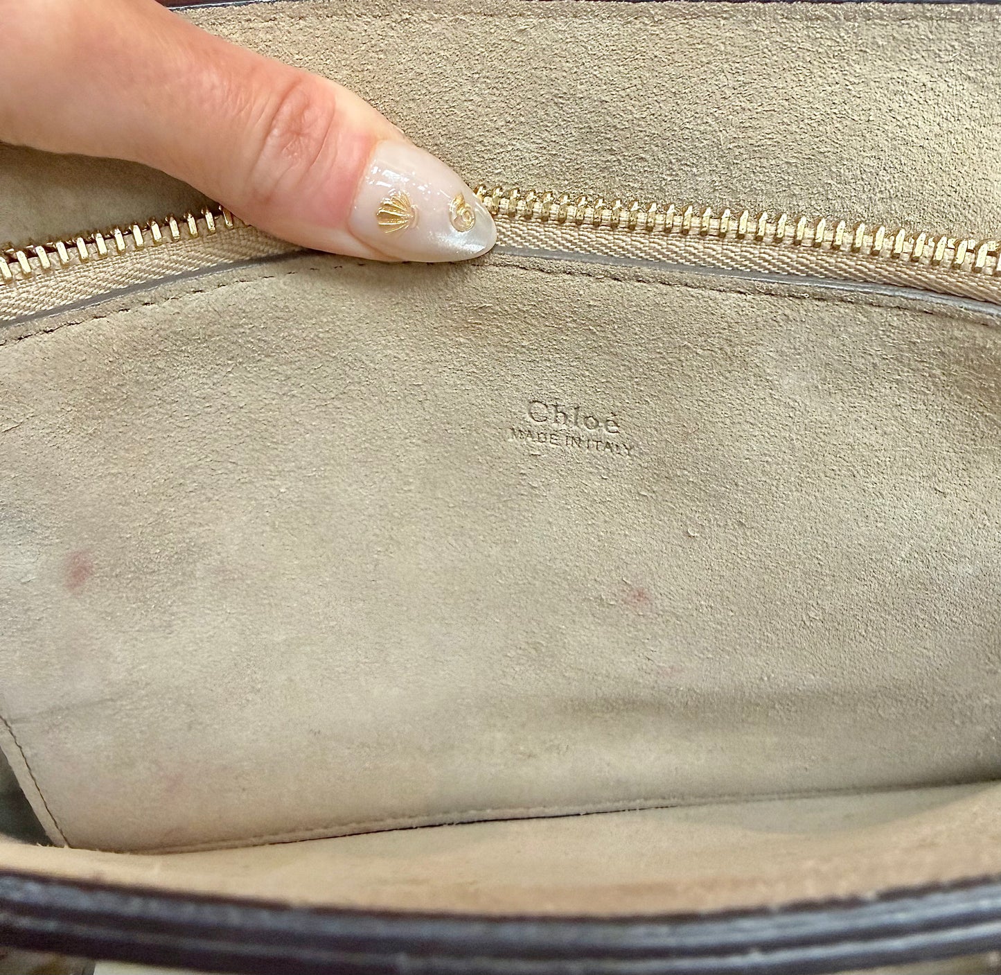 Chloe label on interior suede zipper pocket with light pink staining and wear on the suede.