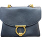 A black pebbled leather shoulder bag with a large gold-tone ring clasp and gold-tone chain strap hardware, shown against a plain white background.
