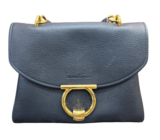 A black pebbled leather shoulder bag with a large gold-tone ring clasp and gold-tone chain strap hardware, shown against a plain white background.