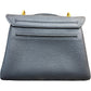Back of a black pebbled leather handbag with gold-tone hardware, against a plain white background.