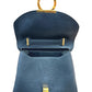A black pebbled leather handbag with gold-tone hardware, shown open with a circular top handle being held by a hand against a white background.