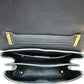 Close-up of the interior of the black handbag, showing multiple interior compartments and gold-tone metal hardware on a white background.