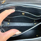 Close-up of the interior of a black leather handbag showing multiple card slots, gold-tone hardware, and a hand keeping the bag open.