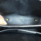 Close-up of the interior of a black leather handbag, showing the lining, and gold-tone hardware.