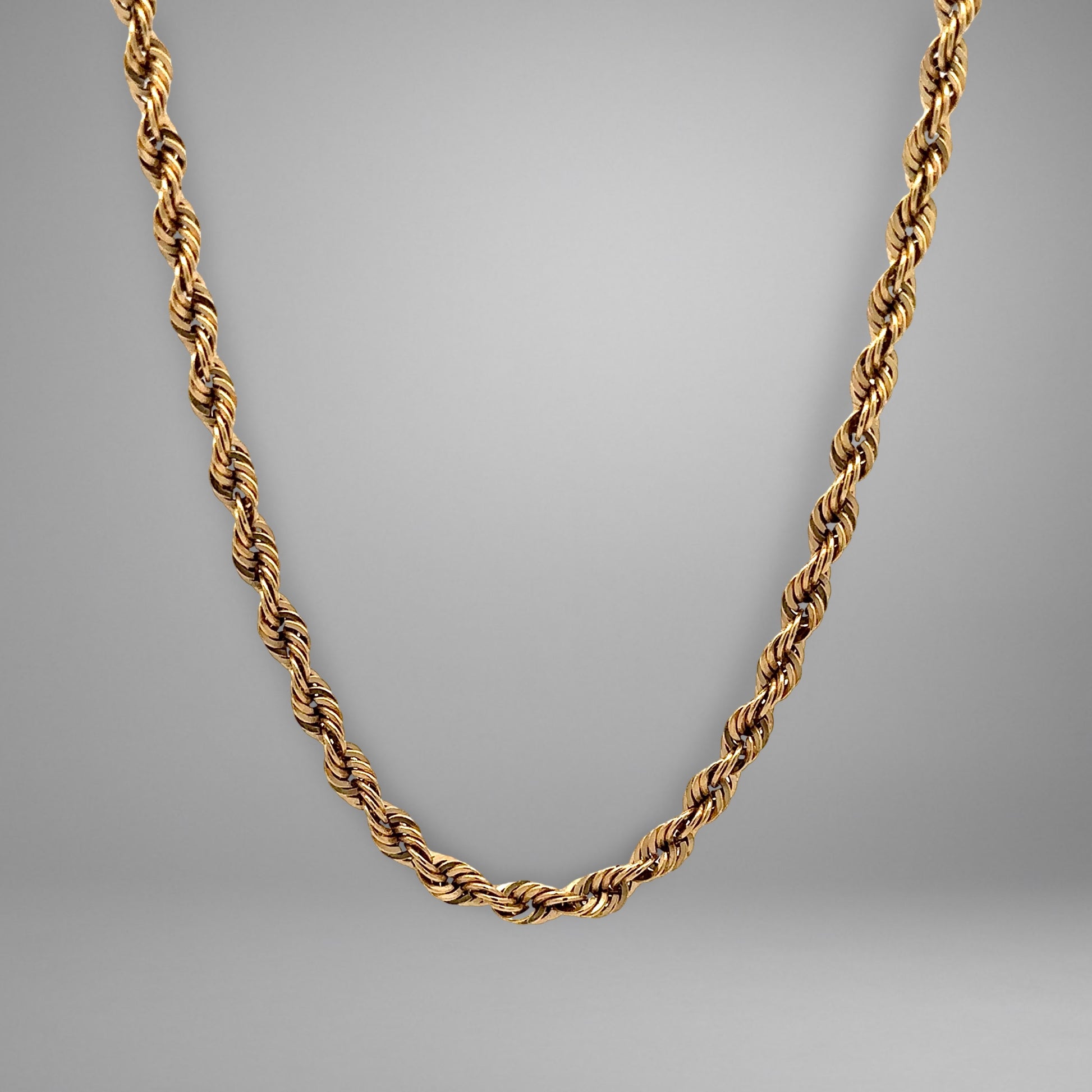 Gold chain necklace on a gray background