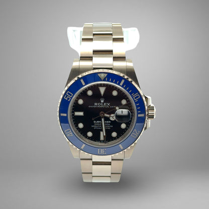 Rolex watch with blue bezel and silver case on gray background