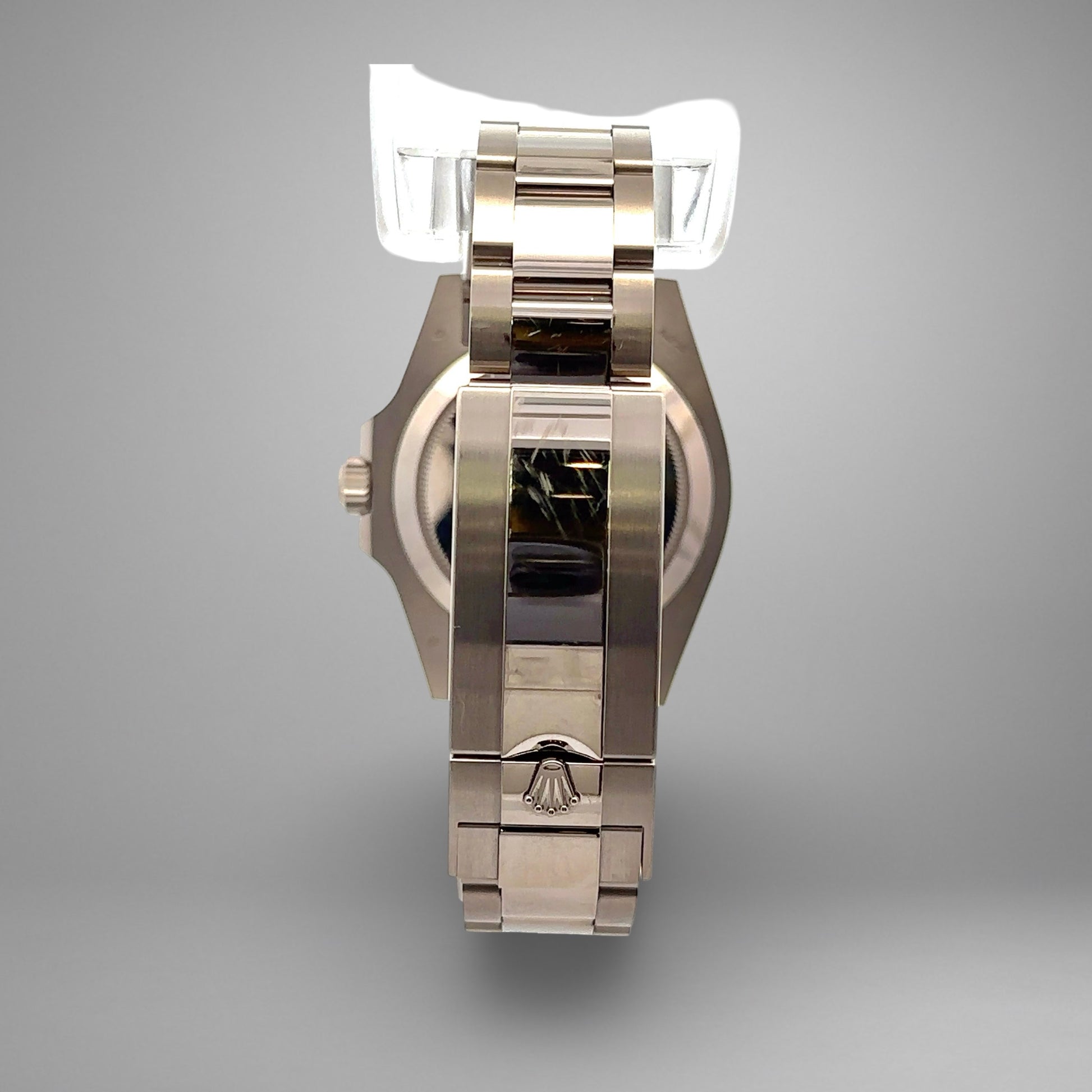 Silver watch with a reflective surface on a gray background. Scratches on band