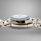 Silver watch with a blue face on a gray background. Nicks on case.