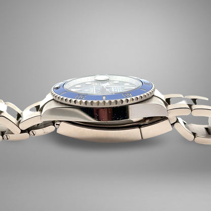 Silver watch with a blue face on a gray background. Nicks on case.