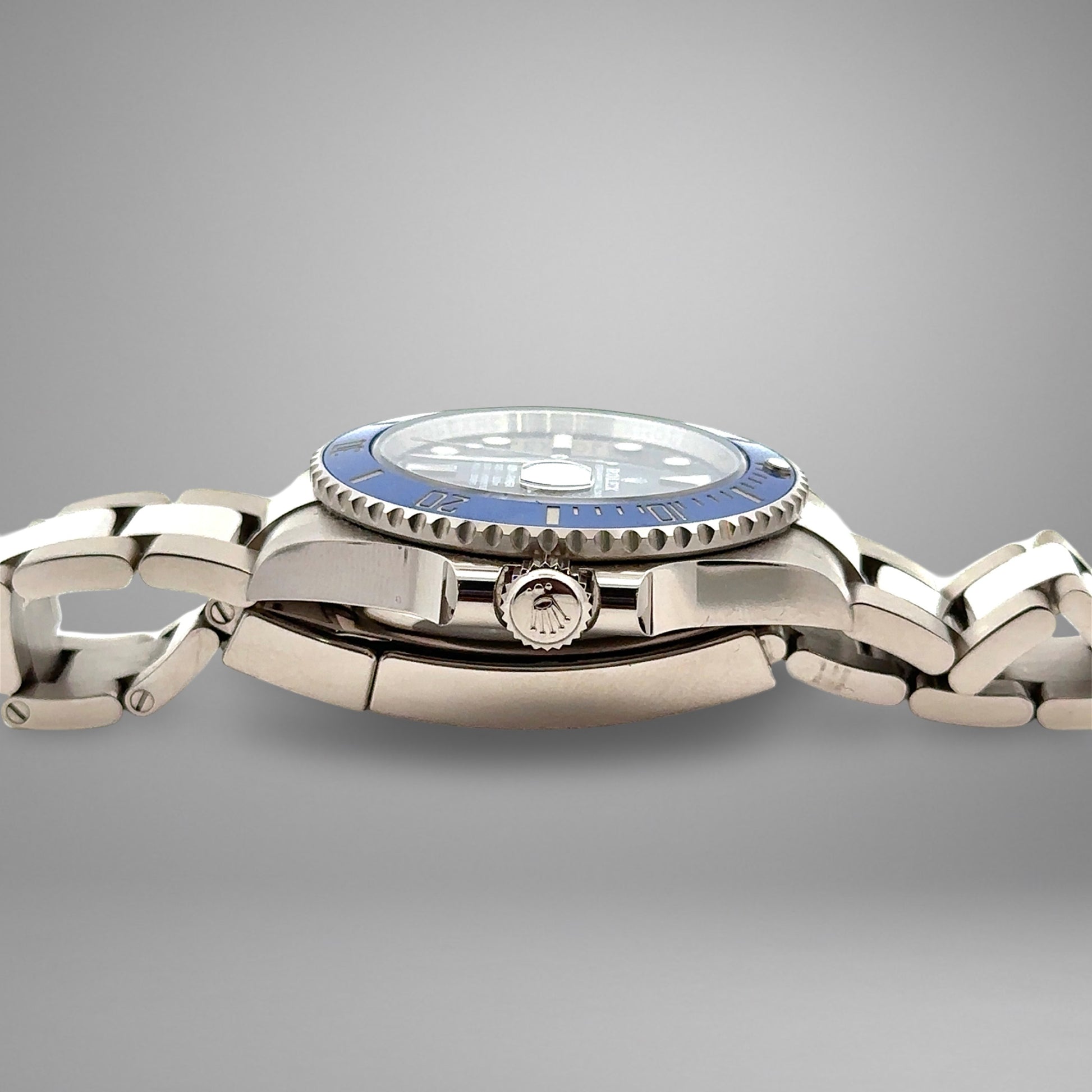 Silver watch with a blue bezel on a gray background