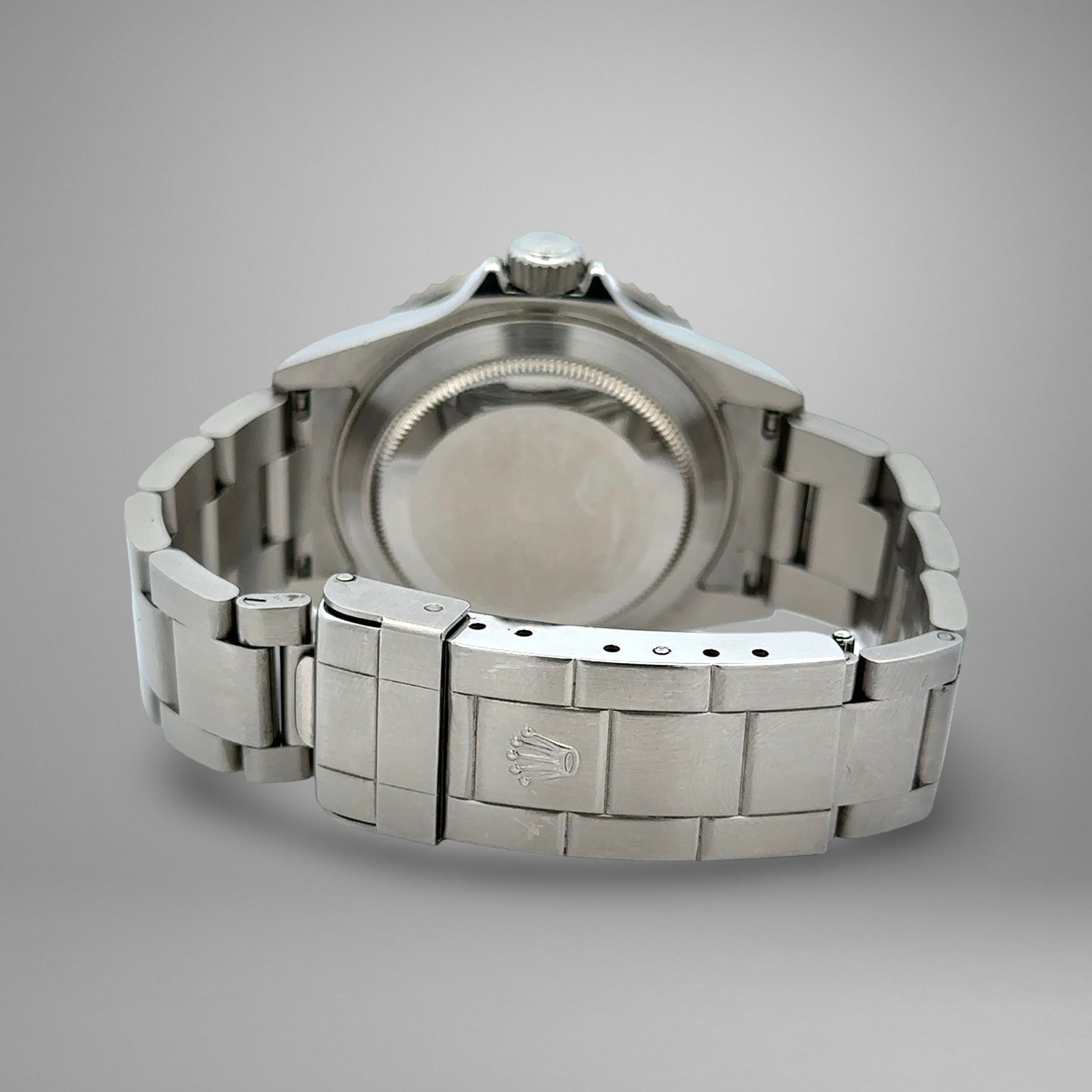 Close-up of a silver watch with a brand logo on a gray background
