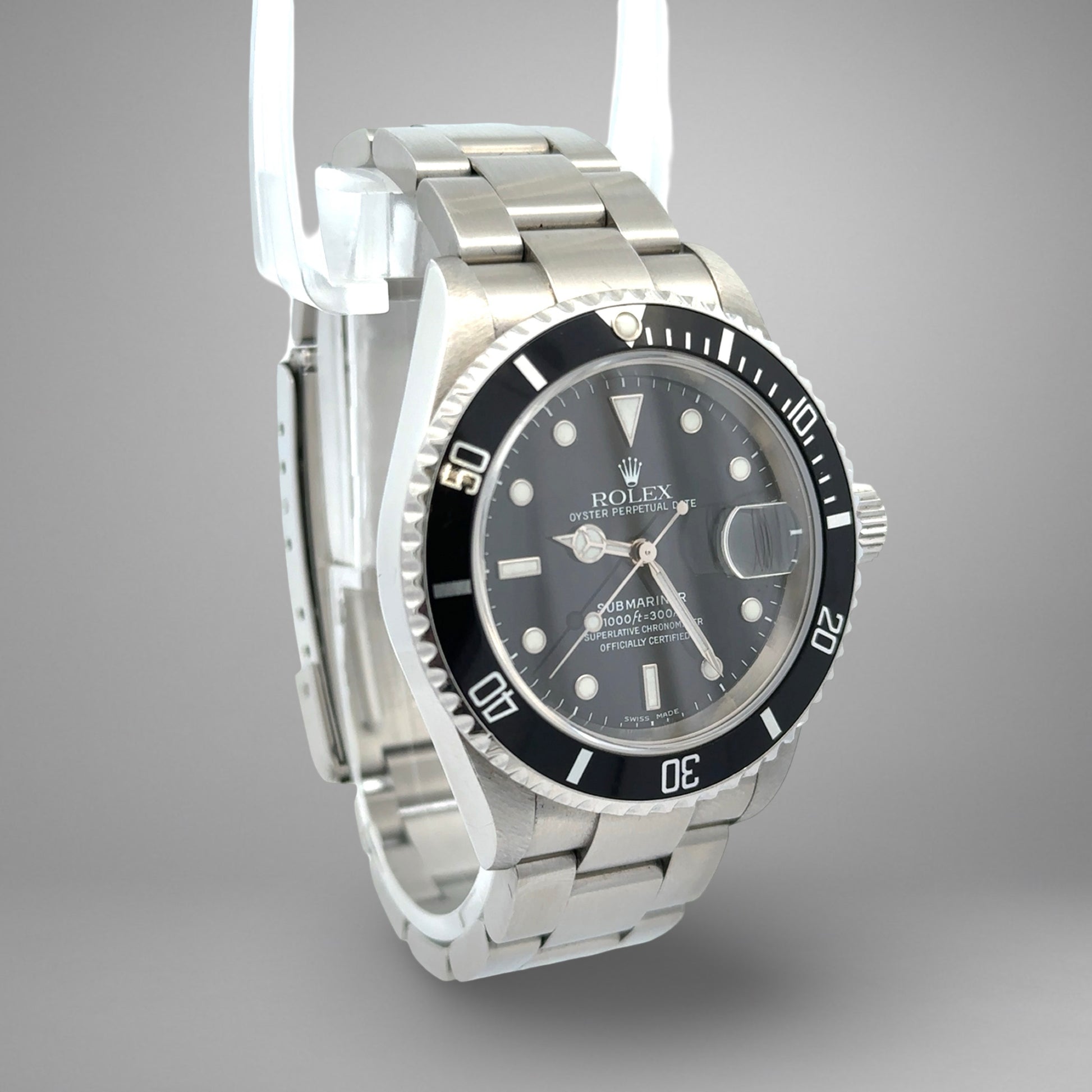 Rolex watch with black dial and silver metal strap on a gray background