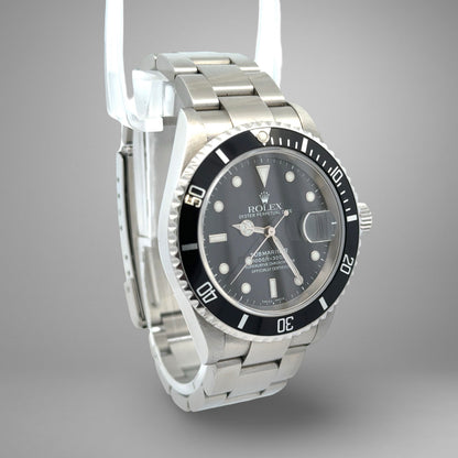 Rolex watch with black dial and silver metal strap on a gray background