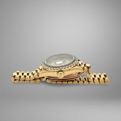 Gold wristwatch with diamond-studded bezel on a gray background