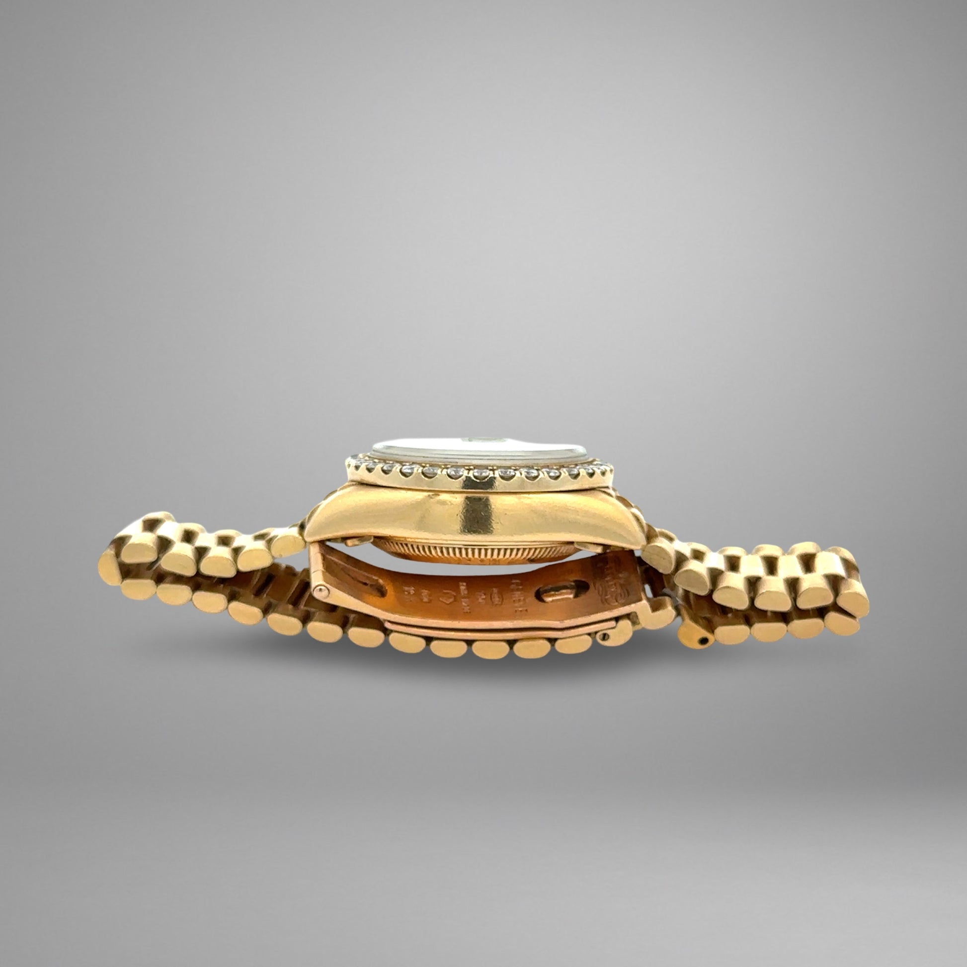 Gold watch with a textured band on a gray background