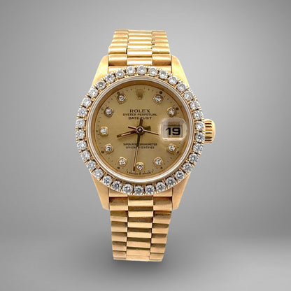 Gold watch with diamond bezel on a gray background