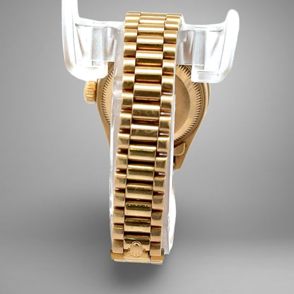 Gold watch with a clear plastic stand on a gray background